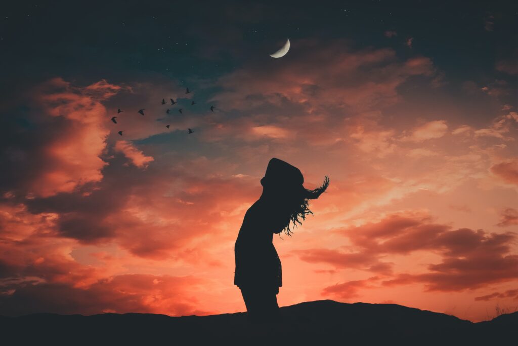 Silhouette of woman at dawn with crescent moon