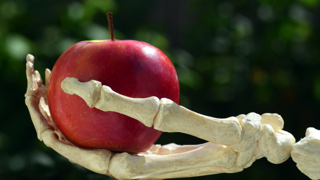 skeleton hand holding a red apple